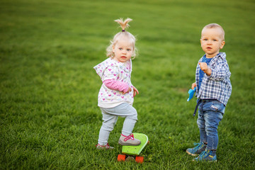 Kids boy and girl playing in the meadow on the green grass.