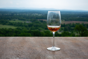 Glass of summer refreshment cocktail staying on granite surface, with great green Forest and hill view on background.