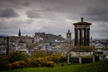 Edinburgh City and Castle, Scotland, viewed from Calton Hill on a cloudy afternoon with the Dugald Stewart monument in the foreground, Scott monument and Balmoral clock tower in background.