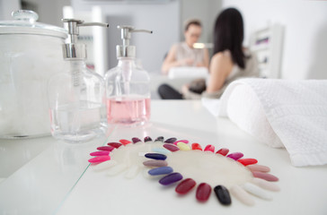 False nails palettes of different colors in nail salon. Colorful artificial nails. Manicure treatment in blurry background