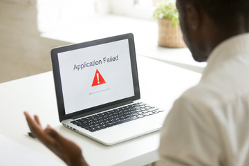 Frustrated unhappy worker getting application fail notice at laptop screen, malware program causing...