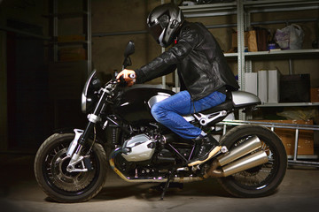 Fototapeta na wymiar Stylish biker sits on his motorcycle in garage