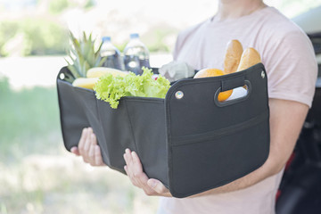 Man holds in his hands big black bag basket full of products