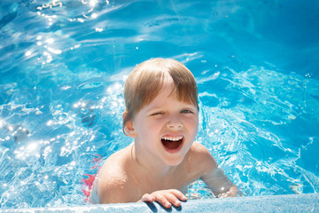 Fototapeta na wymiar little laughing blonde girl swimming in the pool