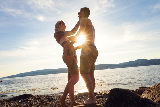Couple in love embrace each other at the beach against sun