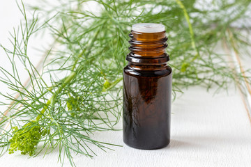 A bottle of dill seed oil with fresh blooming Anethum graveolens