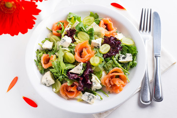 Delicious salad with salmon, grapes and cheese on a white background