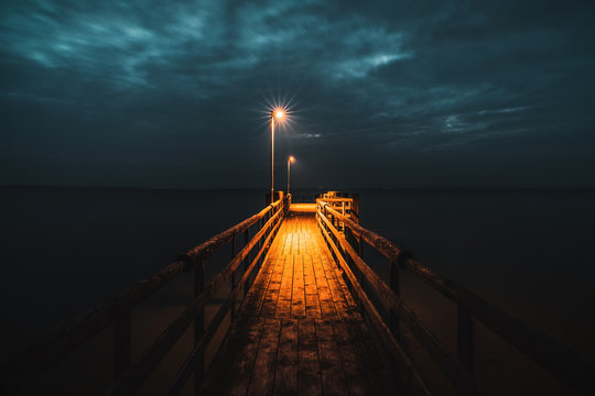 bootssteg am chiemsee zum sp&auml;ten abend in der blauen stunde erhellt das warme licht der laternen die dunkelheit