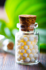 Homeopathy pills bottle wooden eco green leaf background
