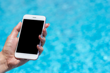 Woman hand using smartphone near swiming pool, close-up