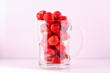 Transparent glass bowl with strawberries on white background