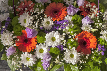 Bouquet of chrysanthemums, gerberas, freesias, anemones and Gypsophila in a purple wicker basket for the bride