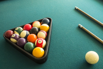 two cue sticks and billiard balls arranged in a triangle