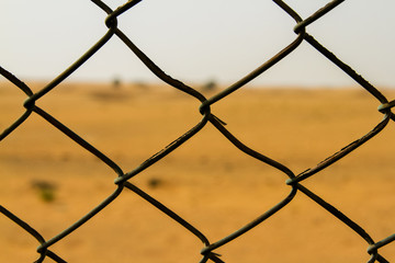 Close up of a chain link fence & desert behind - Al Dhaid, Al Manama, Fujairah, UAE