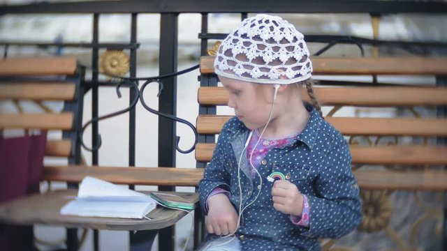 Little stylish beautiful gerl, on city streets listening to music in l headphones.
