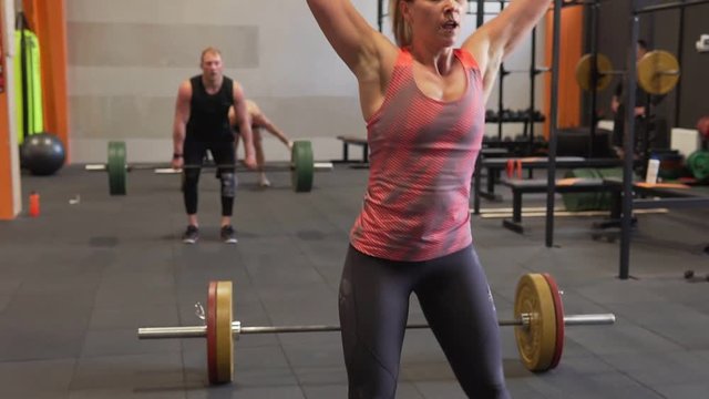Group of fitness people doing power weight lifting workout in gym