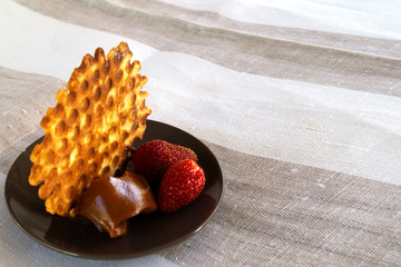A delicate biscuit made from a short-dipped homemade pastry with chocolate pasta and ripe strawberries on a round plate.