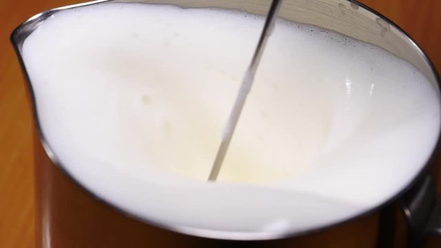 Slow motion shot of frother milk preparing drink for barista purposes, close up