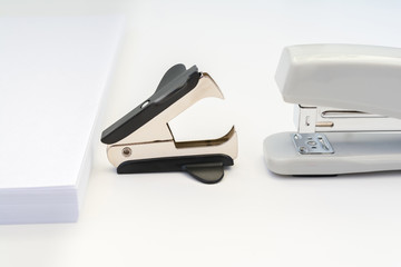 pile of office paper, black staple remover and gray stapler on white background, concept abstract background