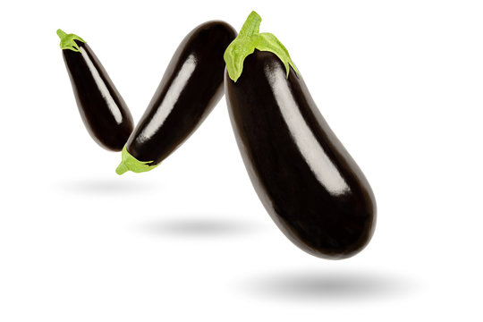 Three eggplants in a row floating in the air, on white background. Solanum melongena, also called aubergine or brinjal. Nightshade. Elongated oval shaped black skinned fruit. Macro food photo closeup.