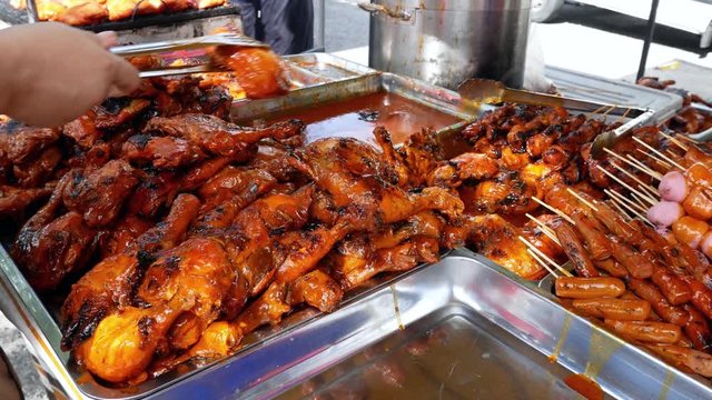 Hawker arranging the tasty ayam madu percik (Honey chicken) on the food container which is selling in Ramadan Bazaar during the holy month of Ramadan.