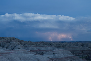 Multiple lightning strikes over the eerie landscape of the Badlands National Park.