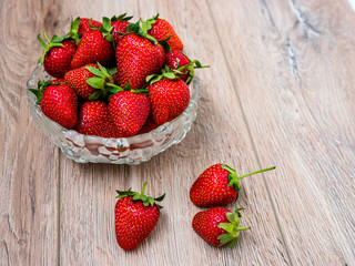 Heap of fresh strawberries in glass bowl on rustic white wooden background