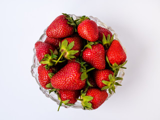 Heap of fresh strawberries in glass bowl on rustic white wooden background, isoated
