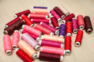 pink and red sewing threads on wood table. top view, selective focus