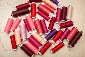 pink and red sewing threads on wood table. top view, selective focus