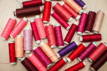 pink and red sewing threads on wood table. top view, selective focus