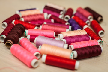 pink and red sewing threads on wood table. top view, selective focus