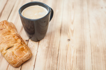Coffee break in the country with cup of freshly brewed coffee with milk and croissan on wooden table top with copyspace