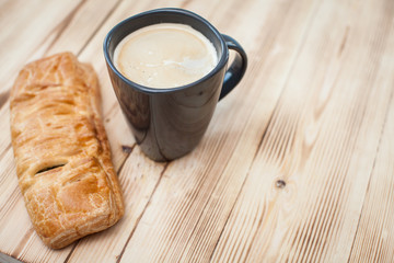 Coffee break in the country with cup of freshly brewed coffee with milk and croissan on wooden table top with copyspace