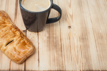 Coffee break in the country with cup of freshly brewed coffee with milk and croissan on wooden table top with copyspace