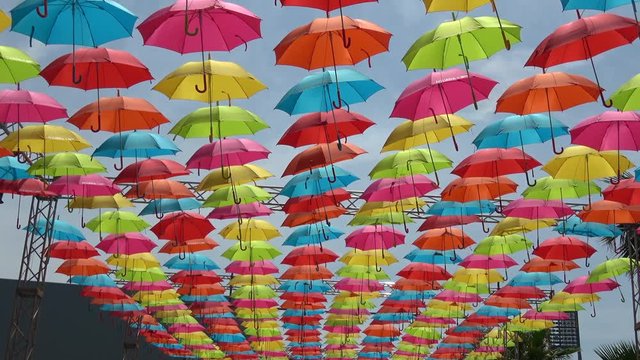 Tilt shot of the colorful umbrellas hanging in the sky, 4K
