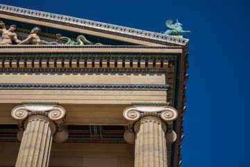 Corner of the pediment on the exterior of the Philadelphia Art Museum, supported by Ionic fluted columns, against a blue sky