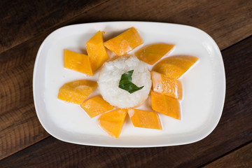 mango sticky rice or Khaoniao mamuang on a wooden table, a traditional thai dessert made with glutinous rice,fresh mango and coconut milk