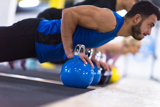 young athletes doing pushups with kettlebells