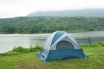 Tent on the grass, with backdrops are reservoirs, forests, mountains and fog, morning.