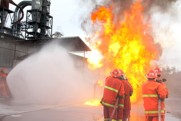 fireman using water and extinguisher to fighting with fire flame in an emergency situation.All firemen wearing fire fighter suit for safety.