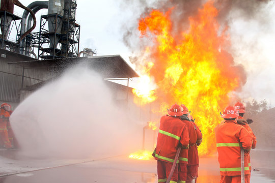  Fireman Using Water And Extinguisher To Fighting With Fire Flame In An Emergency Situation.All Firemen Wearing Fire Fighter Suit For Safety.