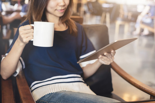 Young woman using tablet in coffee shop drinking coffee