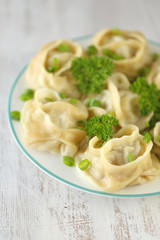 dumplings.  Manty with greens in a round plate on shabby chic background . Manti . Traditional meat dish
