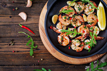 Prawns Shrimps roasted in garlic butter with lemon and parsley on wooden background. Healthy food. Top view. Flat lay.