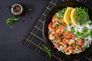 Rice with young green peas, shrimps and arugula in black bowl. Healthy food. Buddha bowl. Top view. Flat lay