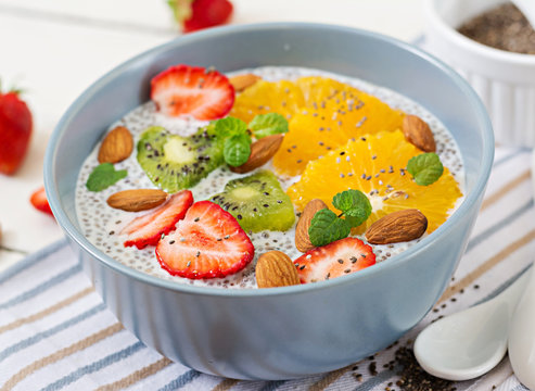 Detox and healthy superfoods breakfast in bowl. Vegan almond milk chia seeds pudding with strawberries, orange and  kiwi.