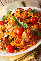 Spaghetti with meat balls, vegetables in a tomato sauce close-up on a plate on a table. vertical, rustic