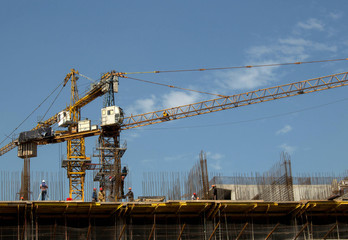 Fototapeta na wymiar building, people in helmets, tower cranes against the sky