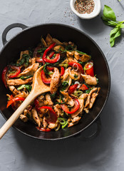 Teriyaki chicken, bell peppers, onions and spinach stir fry in a pan on a gray background, top view